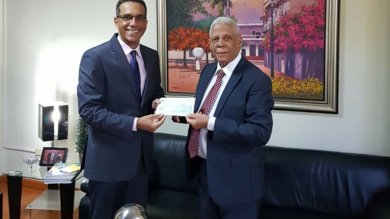 Juan Pumarol entrega a Juan Antigua cheque para apertura comedores económicos en Independencia